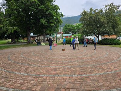 people walking a brick paver labyrinth surrounded by trees