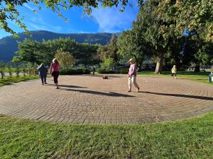people walking a brick paver labyrinth surrounded by trees