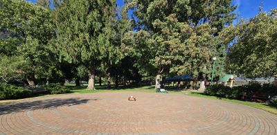 An altar at the center of a brick paver labyrinth with trees in the background