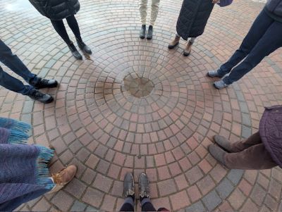 People standing in a circle with only legs and feet showing 